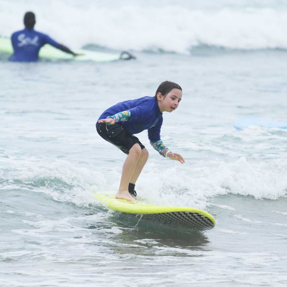 KidsSurfing_girlridingwave_sq kids surf lessons byron bay